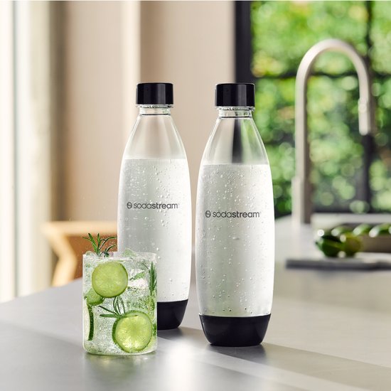 Twee Sodastream flessen met lichte condensatie, naast een glas met munt en limoen.