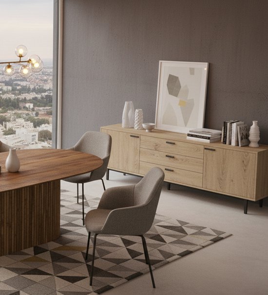 Ovale houten eettafel en stoffen stoelen naast een houten dressoir met een schilderij en vazen.
