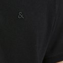 Detail van de linkerborst van een zwarte polo met een geborduurd donker logo.