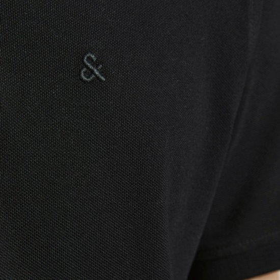 Detail van de linkerborst van een zwarte polo met een geborduurd donker logo.