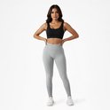 Model in grijze scrunch butt legging en zwarte sportbeha, staand met handen op de heupen.