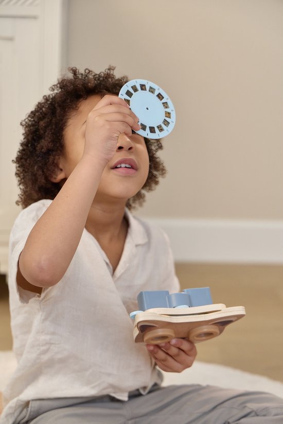Jongetje met krullend haar houdt een blauwe projectieschijf omhoog bij zijn oog.