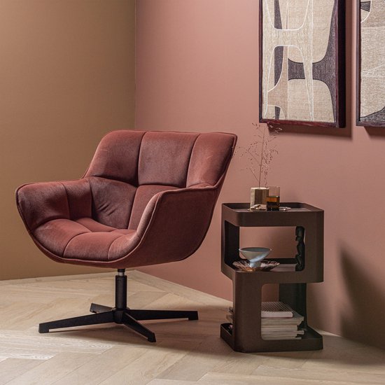 Een bruin fluwelen fauteuil naast een bruin metalen bijzettafel in een woonkamer.