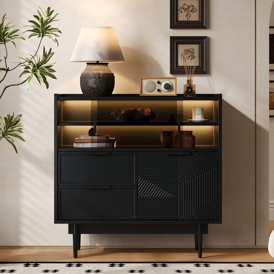 Zwarte kast met twee lades, een geribbelde deur en een glazen deur. Een lamp, radio en decoratie staan bovenop.