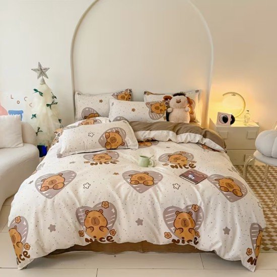 Wit dekbedovertrek met bruine berenprint in hartjes en bloemen, met "NICE" tekst. Bed opgemaakt met kussens en knuffel.