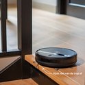 Zwarte robotstofzuiger op een traptrede, met tekst "Rijdt niet van de trap af".