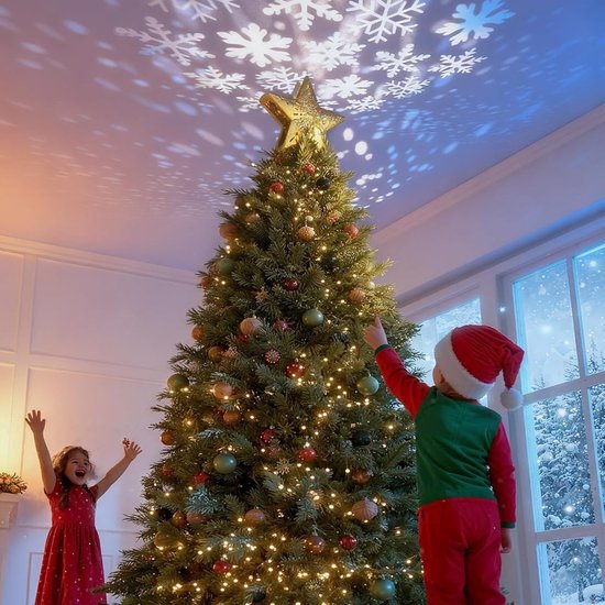 Gouden kerstboomster met projectie van sneeuwvlokken, bekroont een kerstboom versierd met kinderen.