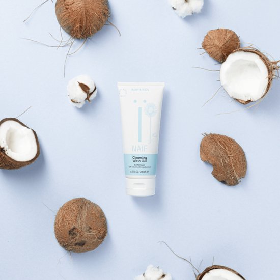 Naïf Cleansing Wash Gel met kokosnoten en katoenbloemen op een blauwe achtergrond.