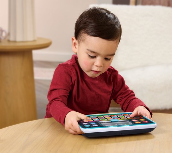 Een jongen met een rood shirt speelt met een blauwgroen alfabet Kindertablet met veel gekleurde knoppen.