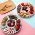 Lichtgroen snackbord met walnoten, kersen, marshmallows, zonnebloempitten. Roze bord ernaast met macrons.