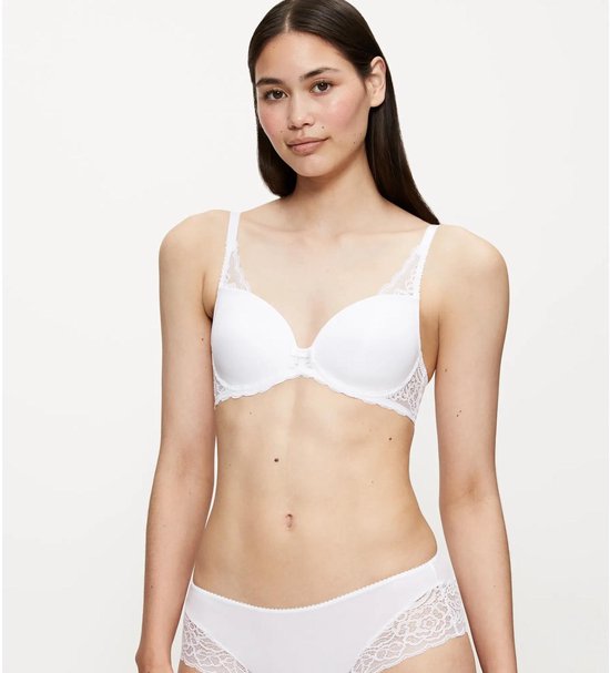 Model draagt een witte beha en slip met kanten details.