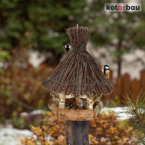 Bruin houten vogelhuisje van wilg met meerdere vogels erop en erin, in een winterse tuin.