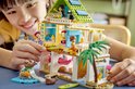 LEGO Friends strandhuis speelset, met twee meisjes die aan het spelen zijn. Blauw huis met roze accenten, groen dak, palmboom en zeehonden.