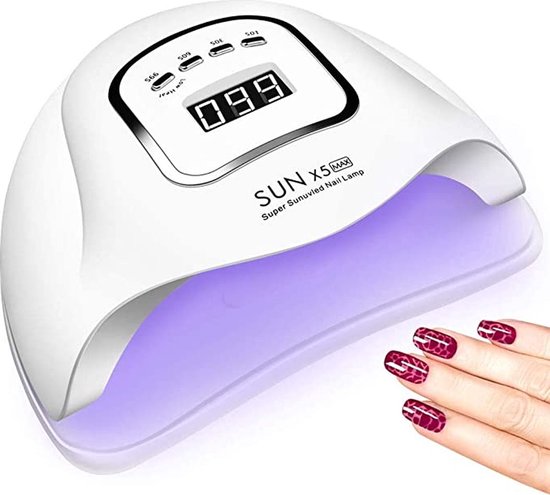 Een witte SUN X5 MAX nagellamp met een digitaal display en verlichte binnenkant. Een hand met donkerrode nagels ligt ernaast.