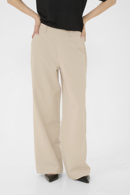 Voeten van een model in een beige wijde broek en zwarte pumps.