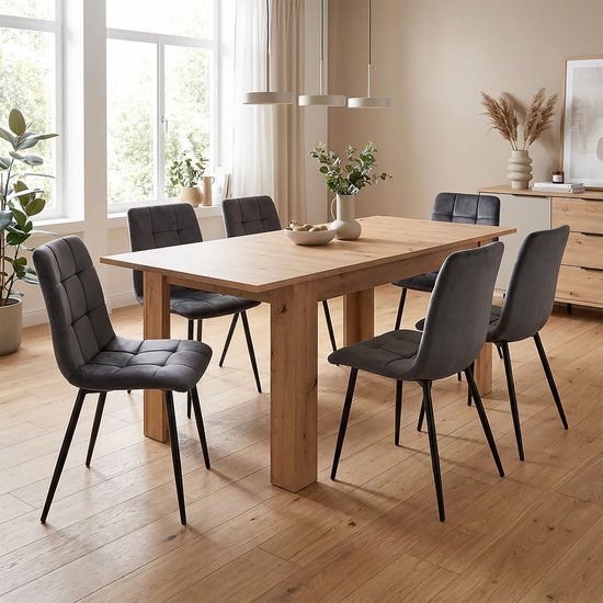 Een ruime eethoek met een uitschuifbare houten tafel en zes grijze stoelen.
