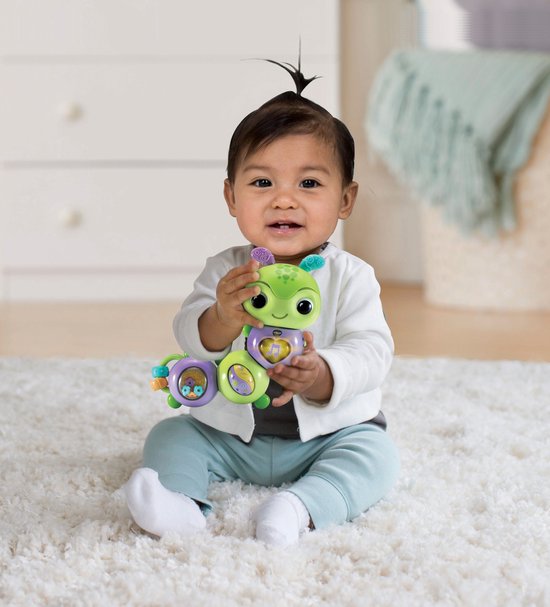 Baby met een groen en paars rupsje met muzieknoot-symbool op de borst.
