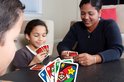 Een gezin speelt UNO Super Mario kaartspel aan tafel.