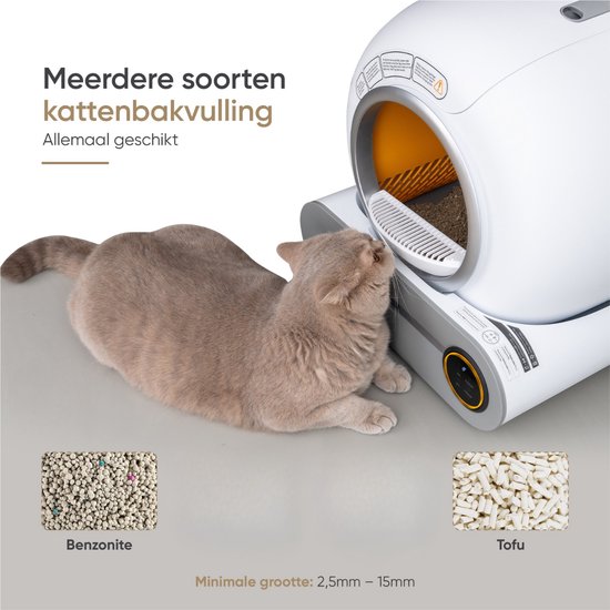 Een Britse Korthaar kat ligt naast de zelfreinigende kattenbak. Twee bakjes met respectievelijk bentoniet en tofu kattenbakvulling zijn zichtbaar.