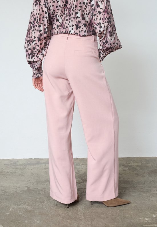 Achterkant van een lichtroze wijde broek, gedragen door een model met een blouse met luipaardprint.