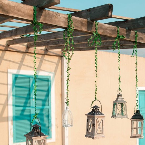 Groene klimop slingers hangen aan een houten pergola met lantaarns