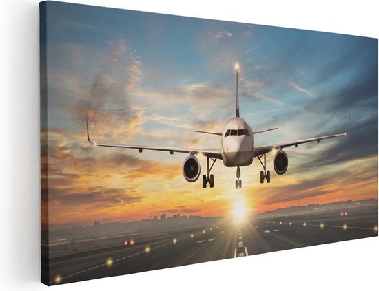 Toile avec un avion atterrissant au coucher du soleil, avec des lumières sur la piste.