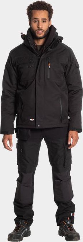 Man in een zwarte Herock werkjas, werkbroek en werkschoenen, met capuchon en oranje accenten.