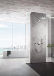 Moderne badkamer met grote ramen, betonlook wanden, vrijstaand bad en inbouw douche met handdouche.