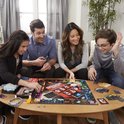 Familie speelt Monopoly Valsspelers Editie rond een tafel met het bordspel, geld en fiches.