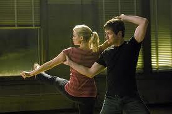 Een man en vrouw dansen samen. De vrouw heeft een been omhoog in een ballet pose.