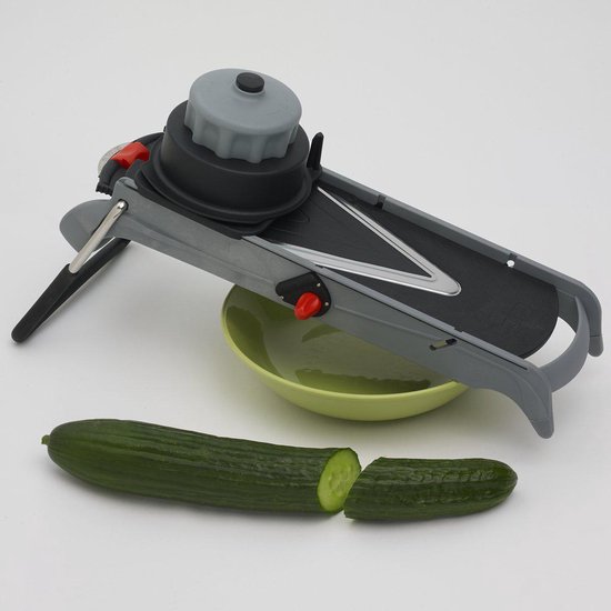Grijze mandoline snijder met rode knop, groene kom en een komkommer.