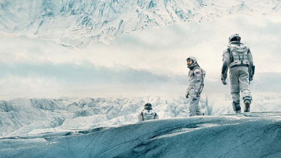 Drie astronauten in witte ruimtepakken staan op een ijzige, besneeuwde ondergrond met bevroren bergen op de achtergrond.
