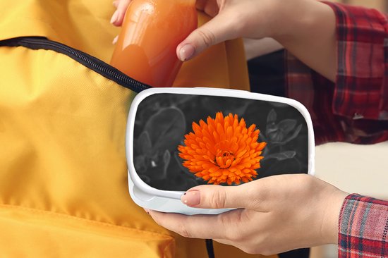 Boîte à pain blanche avec une fleur orange dans des mains, retirée d'un sac à dos jaune.