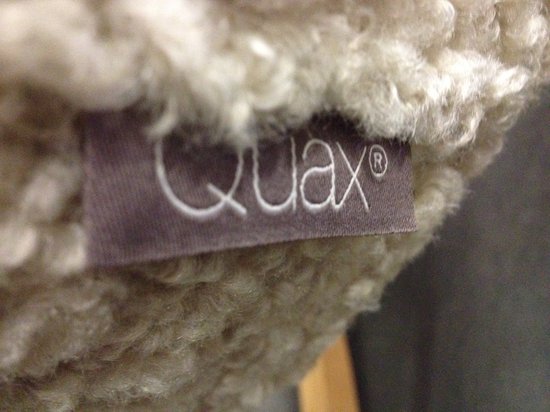 Detailopname van het Quax-label op de teddy ecru stof van de schommelstoel.