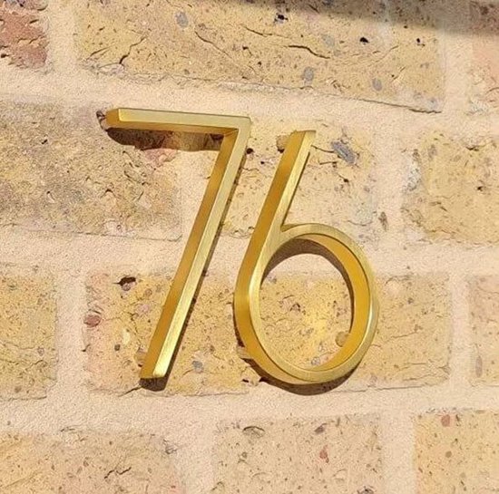 Gouden huisnummer 76 op een bakstenen muur.