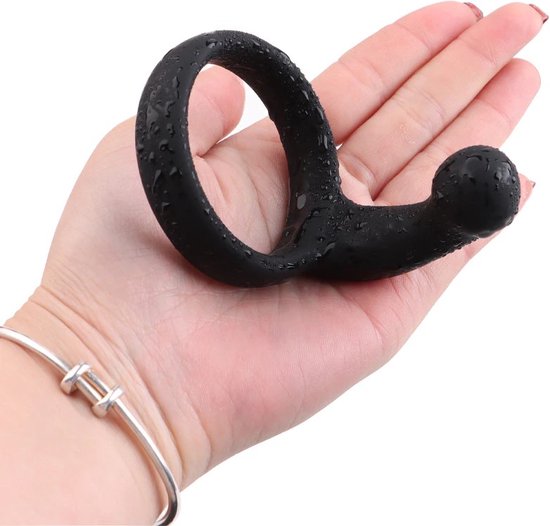 Hand met een natte, zwarte, gebogen penisring in de palm.