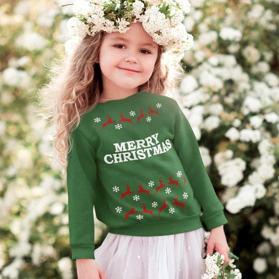 Groene kersttrui voor kinderen met tekst 'Merry Christmas', rendieren en sneeuwvlokken, gedragen door een meisje.