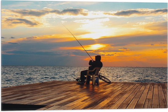 Un homme assis sur une chaise sur une jetée en bois, pêchant au coucher du soleil.