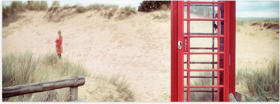 WallClassics - Poster Glanzend – Rode Telefooncel in Duinen - 60x20 cm Foto op Posterpapier met Glanzende Afwerking