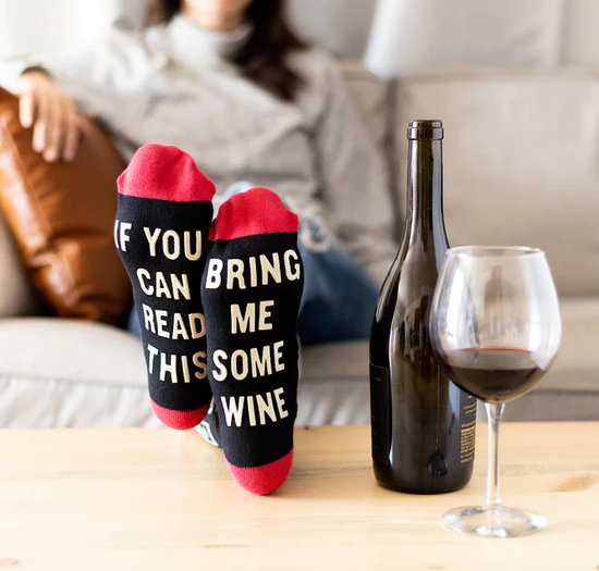 Gedragen sokken met rode boorden en de tekst 'IF YOU CAN READ THIS BRING ME SOME WINE' in gele letters.