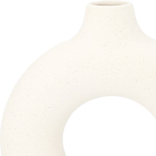 Close-up van een gebroken witte keramiek vaas met een cirkelvormig gat.