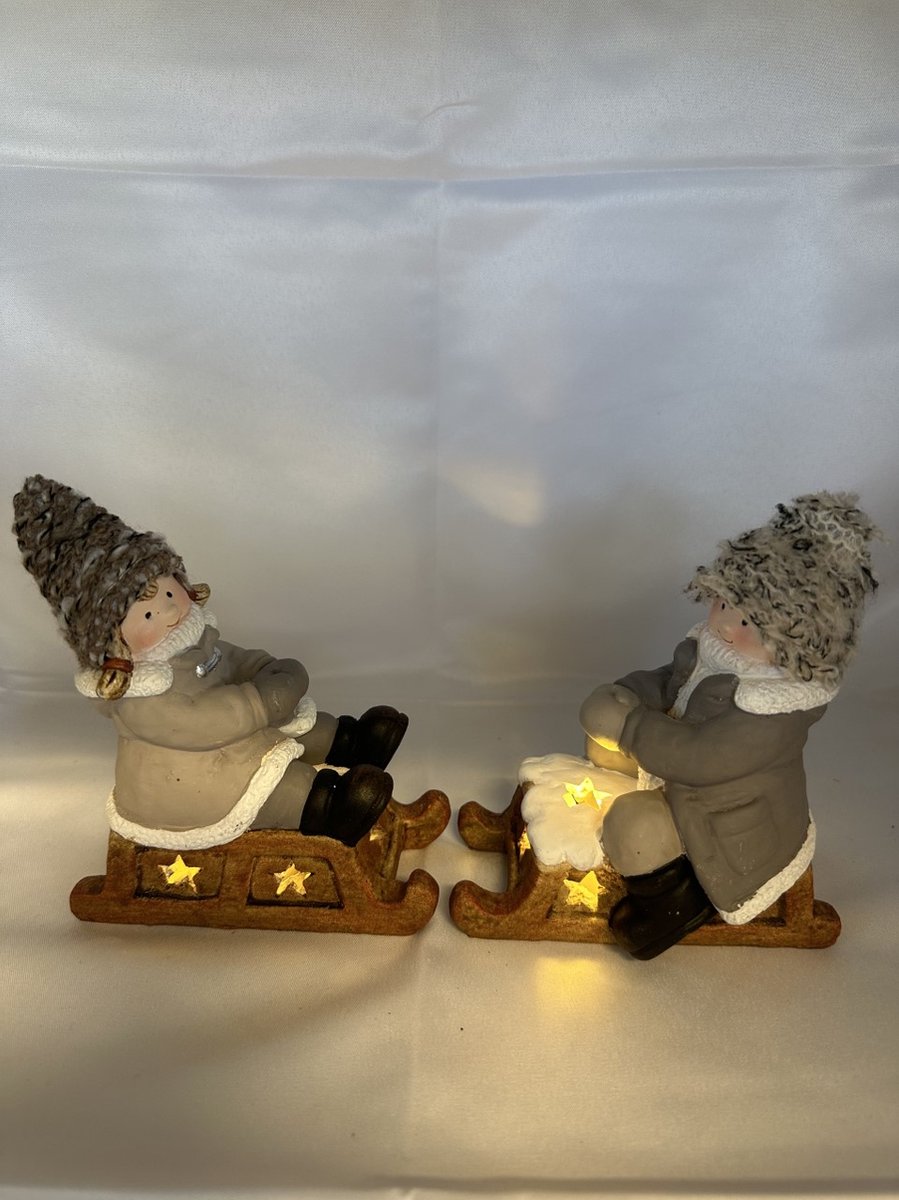 Kerstbeeldjes jongen en meisje op slee met LED - Taupe + taupe gebreide mutsjes - 15 cm hoog x 11 cm x 5cm – Kerstdecoratie