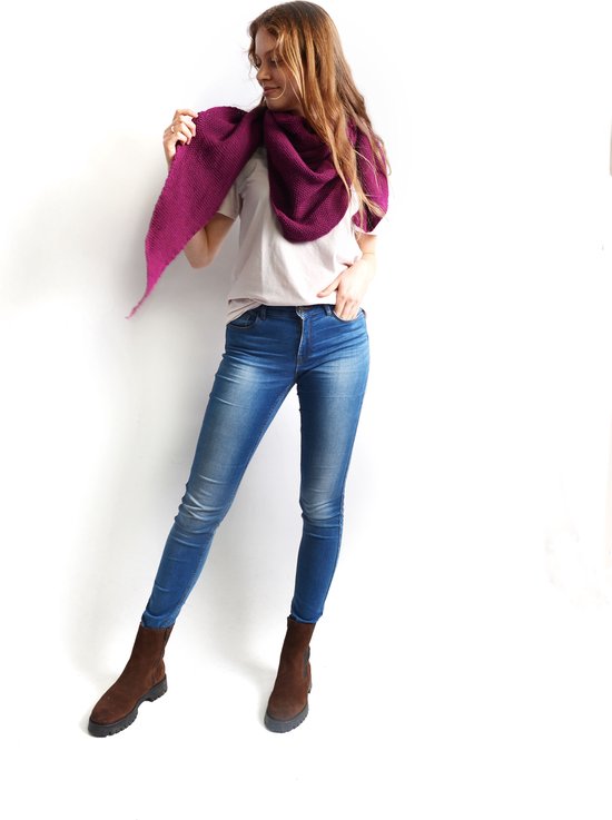 Model draagt een aubergine gebreide driehoekssjaal om haar nek met jeans en bruine laarzen.