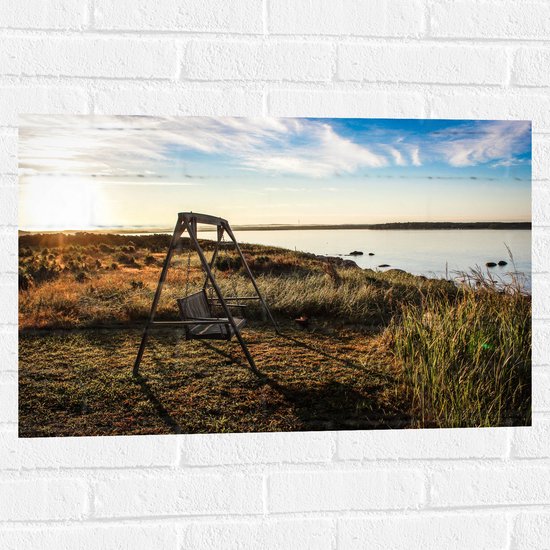 WallClassics - Muursticker - Schommelbank in het Veld aan het Water - 75x50 cm Foto op Muursticker