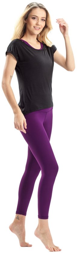 Vrouw in zwarte top en paarse legging, staand op witte achtergrond.