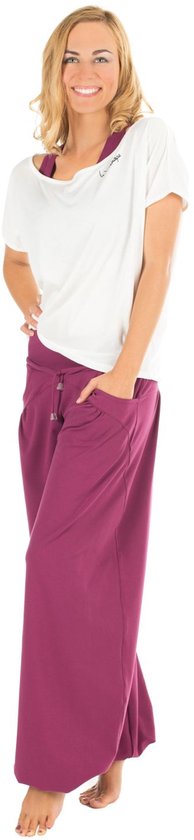 Model in witte off-shoulder top met 'Winshape' logo en paarse wijde broek, met zakken.