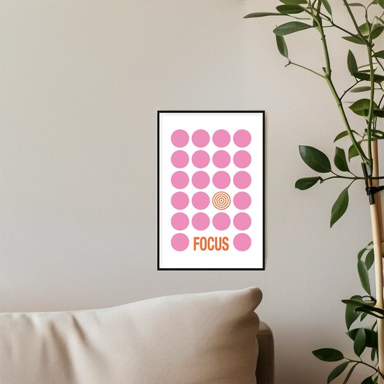 Poster met roze stippen en woord 'FOCUS' in oranje tekst, met een oranje cirkel als middelpunt, aan een muur boven een bank.