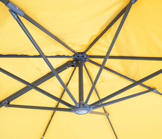 Details van het gele doek en het grijze metalen frame van de zweefparasol.
