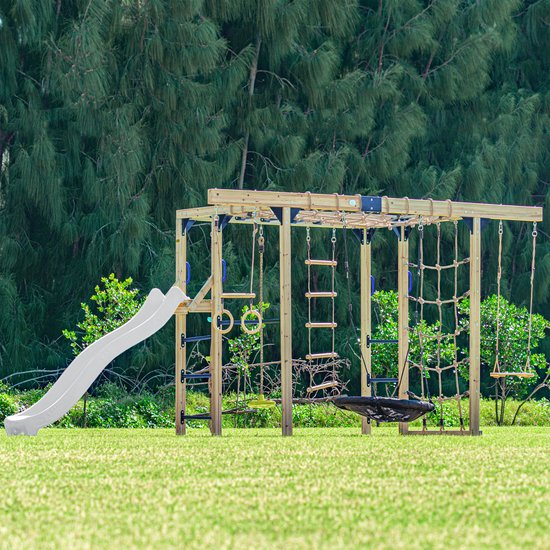 Houten klimtoestel met witte glijbaan, monkey bars, klimnetten, diverse ladders, ringen en schommels op groen gras.