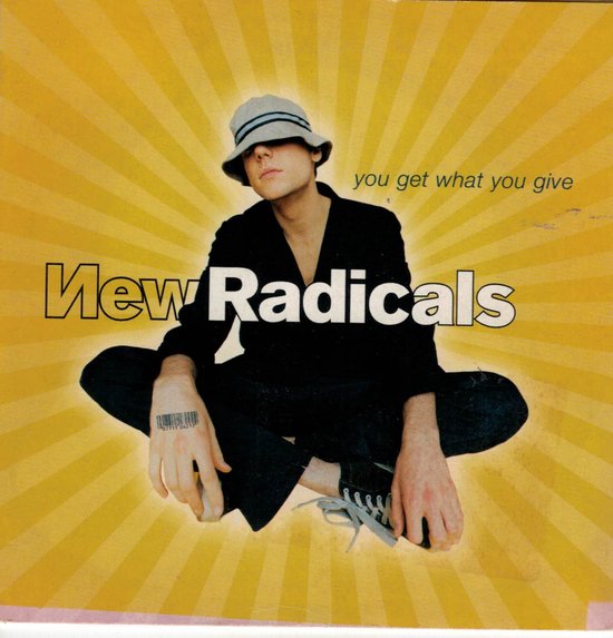 Jongeman in zwarte kleding en grijze hoed, zittend met gekruiste benen. Tekst: 'you get what you give', 'New Radicals'.